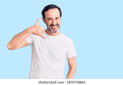 Middle age handsome man wearing casual t-shirt smiling doing phone gesture with hand and fingers like talking on the telephone. communicating concepts.  - Shutterstock ID 1874710864