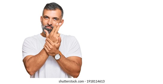 Middle Age Handsome Man Wearing Casual White Tshirt Holding Symbolic Gun With Hand Gesture, Playing Killing Shooting Weapons, Angry Face 