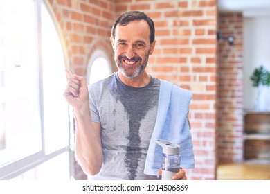 Middle Age Handsome Sportman Sweaty Holding Bottle Of Water And Towel After Exercise At Gym Very Happy Pointing With Hand And Finger To The Side