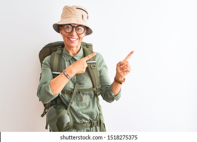 Middle Age Hiker Woman Wearing Backpack Canteen Hat Glasses Over Isolated White Background Smiling And Looking At The Camera Pointing With Two Hands And Fingers To The Side.