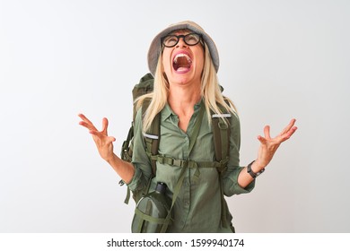 Middle Age Hiker Woman Wearing Backpack Hat Canteen Glasses Over Isolated White Background Crazy And Mad Shouting And Yelling With Aggressive Expression And Arms Raised. Frustration Concept.