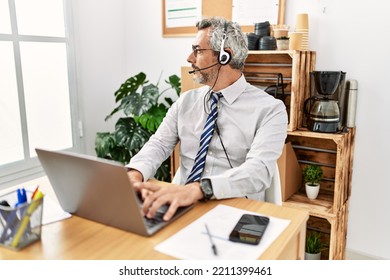 Middle Age Hispanic Business Man Working At The Office Wearing Operator Headset Looking To Side, Relax Profile Pose With Natural Face With Confident Smile. 