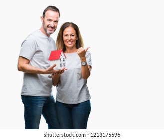 Middle age hispanic casual couple buying new house over isolated background pointing and showing with thumb up to the side with happy face smiling