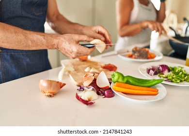 Middle Age Hispanic Couple Cooking At Kitchen