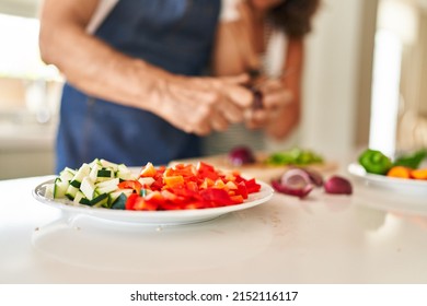 Middle Age Hispanic Couple Cooking At Kitchen