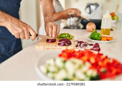 Middle Age Hispanic Couple Cooking At Kitchen