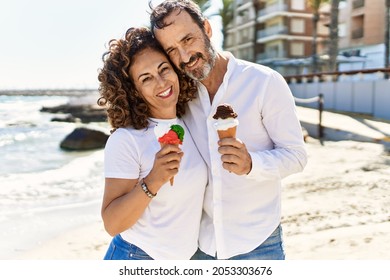 Middle age hispanic couple hugging and eating ice cream at the beach. - Powered by Shutterstock