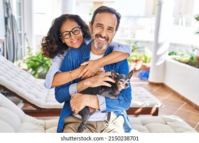 Middle age hispanic couple hugging each other sitting on hammock with dog at terrace - Powered by Shutterstock