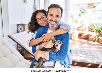 Middle age hispanic couple hugging each other sitting on hammock with dog at terrace - Powered by Shutterstock