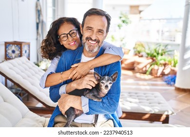 Middle age hispanic couple hugging each other sitting on hammock with dog at terrace - Powered by Shutterstock