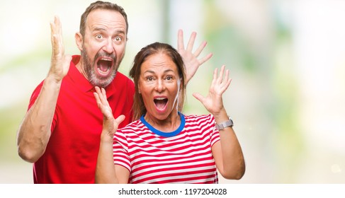 Middle age hispanic couple in love over isolated background celebrating crazy and amazed for success with arms raised and open eyes screaming excited. Winner concept - Shutterstock ID 1197204028