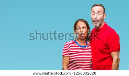 Middle age hispanic couple in love over isolated background making fish face with lips, crazy and comical gesture. Funny expression.