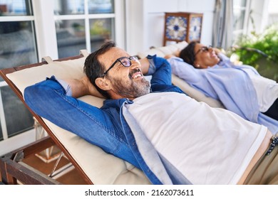 Middle age hispanic couple relaxed with hands on head lying on hammock at terrace - Powered by Shutterstock