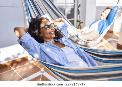 Middle age hispanic couple relaxed with hands on head lying on hammock at terrace - Powered by Shutterstock