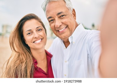 Middle age hispanic couple smiling happy making selfie by the camera at the beach. - Powered by Shutterstock