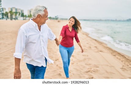 Middle Age Hispanic Couple Smiling Happy Walking At The Beach.