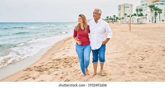 Middle Age Hispanic Couple Smiling Happy Walking At The Beach.