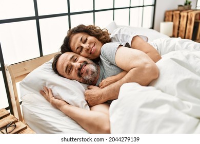 Middle age hispanic couple smiling happy and hugging lying on the bed at home. - Powered by Shutterstock