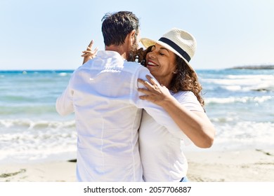 Middle Age Hispanic Couple Smiling Happy Dancing At The Beach.