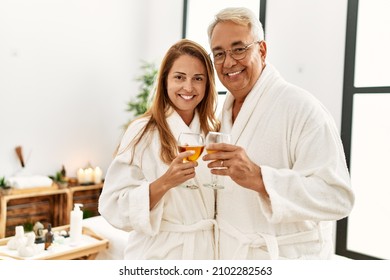 Middle age hispanic couple smiling happy drinking champagne at wellness center.