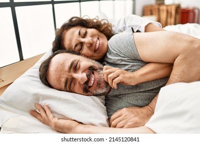 Middle age hispanic couple smiling happy and hugging lying on the bed at home. - Powered by Shutterstock