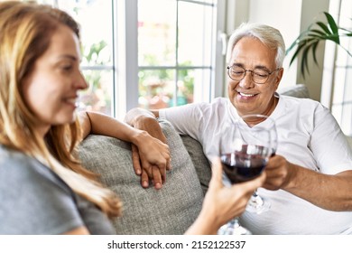 Middle Age Hispanic Couple Smiling Happy Drinking Wine Sitting On The Sofa At Home.