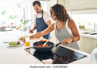 Middle Age Hispanic Couple Smiling Confident Cooking At Kitchen