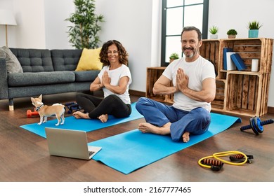 Middle Age Hispanic Couple Smiling Happy Doing Online Yoga Class At Home.