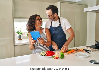 Middle age hispanic couple smiling confident cooking and using touchpad at kitchen - Powered by Shutterstock