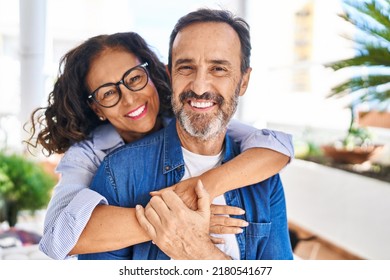 Middle age hispanic couple smiling confident hugging each other sitting on hammock at terrace - Shutterstock ID 2180541677