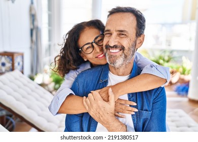 Middle age hispanic couple smiling confident hugging each other sitting on hammock at terrace - Shutterstock ID 2191380517