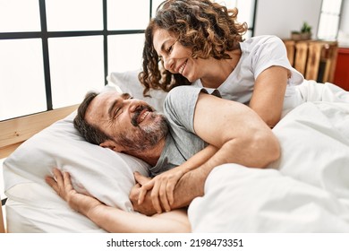 Middle age hispanic couple smiling happy and hugging lying on the bed at home. - Powered by Shutterstock