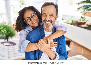 Middle age hispanic couple smiling confident hugging each other sitting on hammock at terrace - Shutterstock ID 2200161449