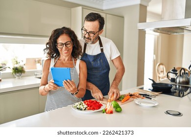 Middle age hispanic couple smiling confident cooking and using touchpad at kitchen - Powered by Shutterstock