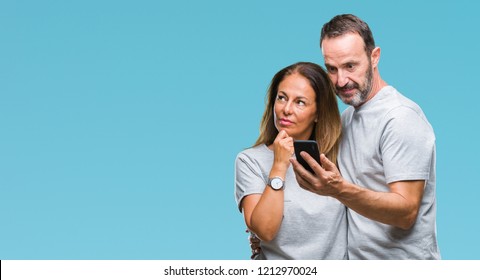 Middle Age Hispanic Couple Texting Message On Smartphone Ver Isolated Background Serious Face Thinking About Question, Very Confused Idea