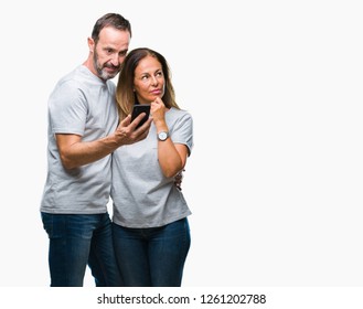 Middle Age Hispanic Couple Texting Message On Smartphone Ver Isolated Background Serious Face Thinking About Question, Very Confused Idea