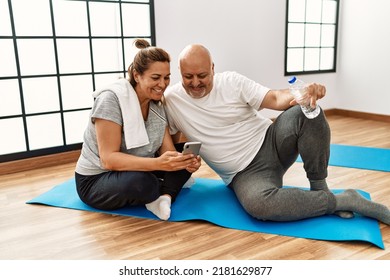 Middle Age Hispanic Couple Using Smartphone At Sport Center.