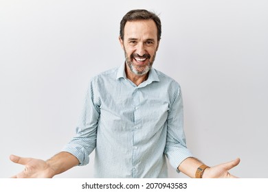 Middle age hispanic man with beard standing over isolated background smiling cheerful with open arms as friendly welcome, positive and confident greetings  - Shutterstock ID 2070943583