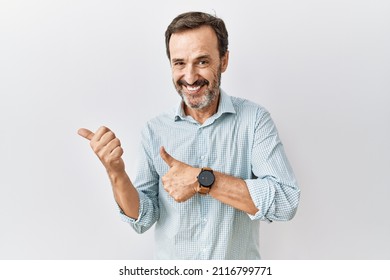 Middle Age Hispanic Man With Beard Standing Over Isolated Background Pointing To The Back Behind With Hand And Thumbs Up, Smiling Confident 