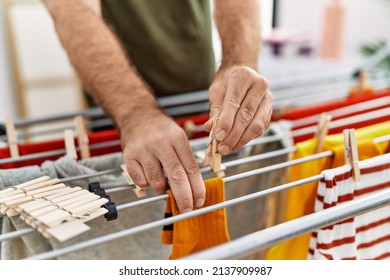 Middle Age Hispanic Man Hanging Clothes At Clothesline At Laundry Room