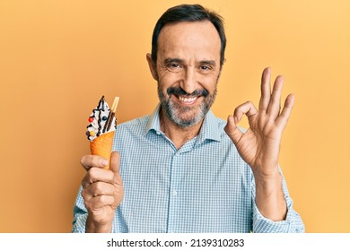 Middle Age Hispanic Man Holding Ice Cream Doing Ok Sign With Fingers, Smiling Friendly Gesturing Excellent Symbol 