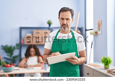 Middle age hispanic man painting on art notebook with pencils depressed and worry for distress, crying angry and afraid. sad expression. 