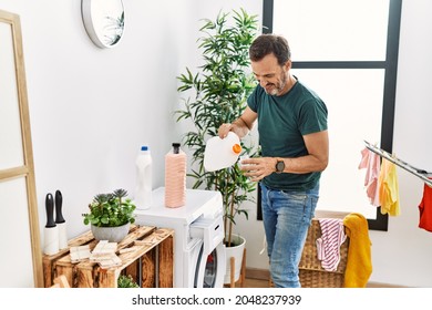 Middle age hispanic man smiling happy doing laundry at home. - Powered by Shutterstock