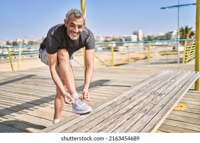 Middle age hispanic man smiling confident tying shoe at street - Powered by Shutterstock