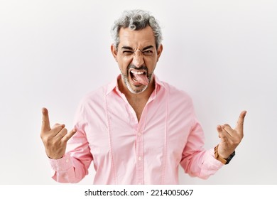 Middle Age Hispanic Man Standing Over Isolated Background Shouting With Crazy Expression Doing Rock Symbol With Hands Up. Music Star. Heavy Concept. 