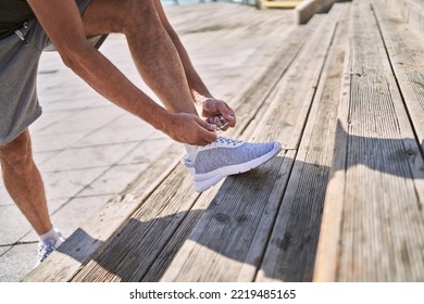 Middle Age Hispanic Man Tying Shoe At Street