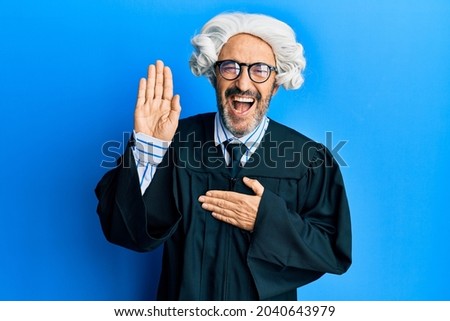 Middle age hispanic man using gavel smiling and laughing hard out loud because funny crazy joke. 