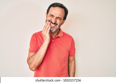 Middle age hispanic man wearing casual clothes touching mouth with hand with painful expression because of toothache or dental illness on teeth. dentist 