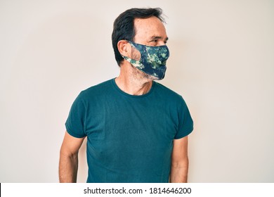 Middle Age Hispanic Man Wearing Covid-19 Protection Mask Looking Away To Side With Smile On Face, Natural Expression. Laughing Confident. 