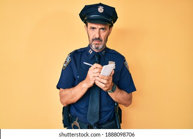 Middle Age Hispanic Man Wearing Police Uniform Writing Traffic Fine Relaxed With Serious Expression On Face. Simple And Natural Looking At The Camera. 